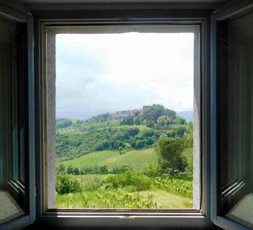 a window with a view of a green hill at Podere Orto Wine Country House in Trevinano