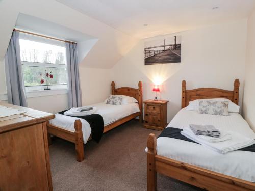 a bedroom with two beds and a window at Barley Cottage in Newton Stewart