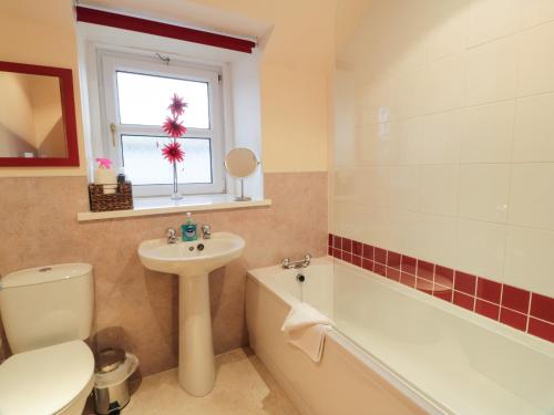 La salle de bains est pourvue d'un lavabo, de toilettes et d'une baignoire. dans l'établissement Barley Cottage, à Newton Stewart