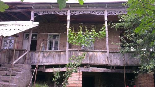 an old wooden house with a wooden porch at Gia's Home in Vazisubani in Vazisubani