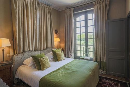 a bedroom with a bed with green pillows and a window at Château Des Briottieres in Champigné