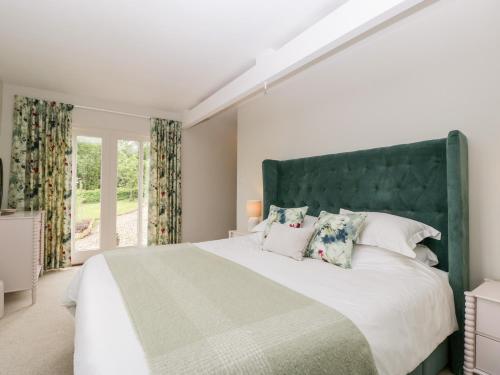 a bedroom with a large bed with a green headboard at The Shippon in Honiton