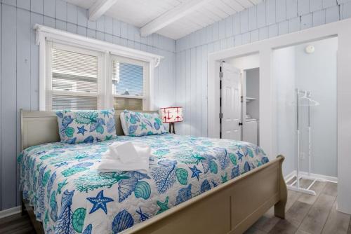 Schlafzimmer mit einem Bett mit einer blauen und weißen Bettdecke in der Unterkunft Anchor Haven Ocean Views in Oak Island