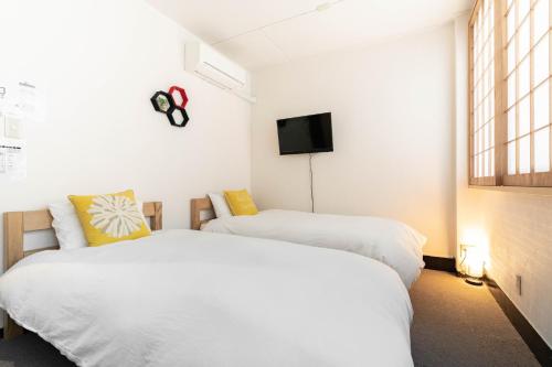 a bedroom with two beds and a tv on the wall at 鶴橋妙宅 in Osaka