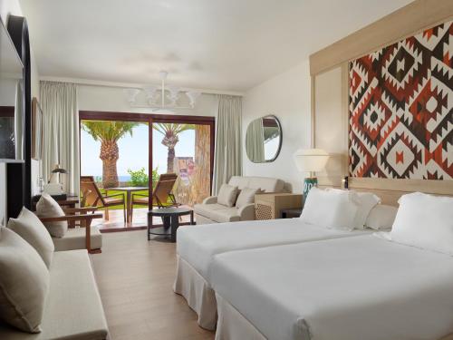 une chambre d'hôtel avec deux lits et un salon dans l'établissement H10 Playa Meloneras Palace, à Meloneras