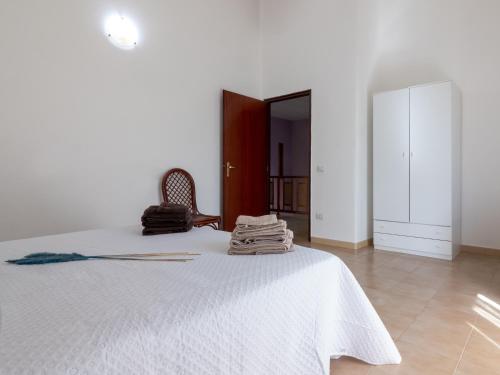 a bedroom with a bed with white sheets and a chair at Butterfly House in Trappeto