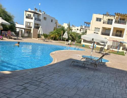 a swimming pool with a chair and an umbrella at Modern Studio apartment Armonia Court in Paralimni