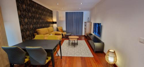 a living room with a table and chairs and a television at Lugar de Alegría, Pegado a Playa, 2 Hab, 6 p, Wifi - VUT-4241-AS in Gijón