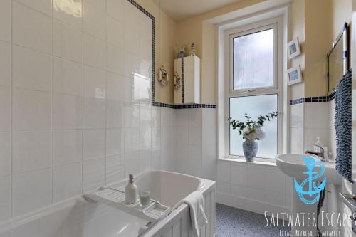 a white bathroom with a tub and a window at Sea Spray Villa, Brixham in Brixham