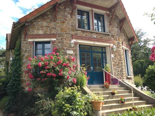 a stone house with a blue door and flowers at Le Chant Des Oiseaux in Magny-les-Hameaux