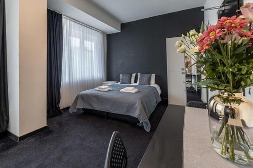 - une chambre avec un lit et un vase de fleurs dans l'établissement Albert gare du Midi 31, à Bruxelles