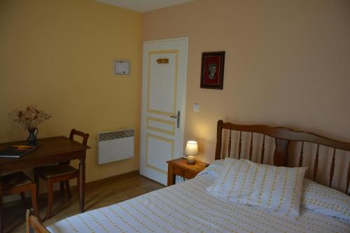 ein Schlafzimmer mit einem Bett und einem Schreibtisch sowie einem Tisch mit einer Lampe in der Unterkunft Chambre d'hôtes de la tuilerie in Rion-des-Landes