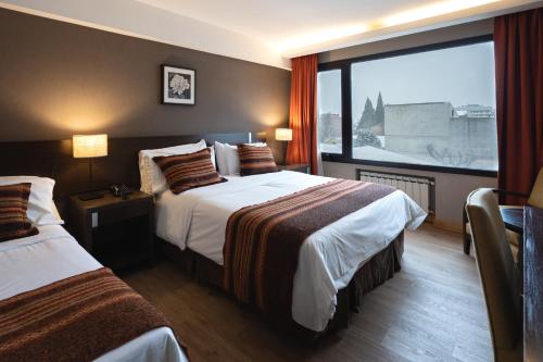 Habitación de hotel con 2 camas y ventana grande. en Hotel Crans Montana en San Carlos de Bariloche