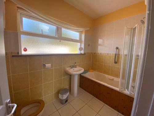 a bathroom with a sink and a toilet and a bath tub at Dunmanus Cottage West Cork in Durrus