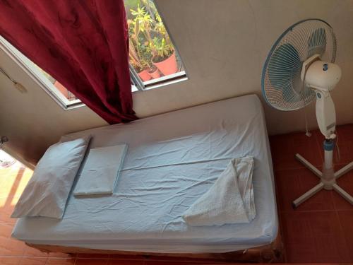 a bed in a room with a fan and a window at Guest House Nena in Moyogalpa