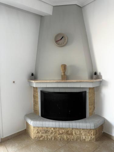 a living room with a fireplace with a clock on the wall at Kallikratis Apartment Near Athens Airport in Spáta