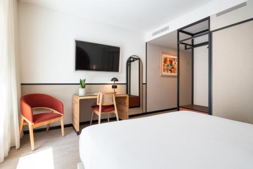 a hotel room with a bed and a desk and a tv at The Editory Garden Porto Hotel in Porto