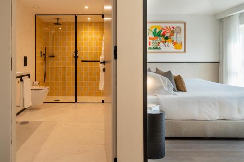 a bedroom with a bed and a bathroom with a shower at The Editory Garden Porto Hotel in Porto