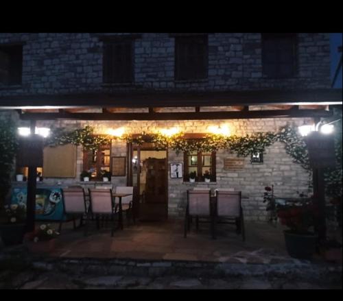 a patio at night with chairs and lights at Karpouzis guesthouse in Víkos