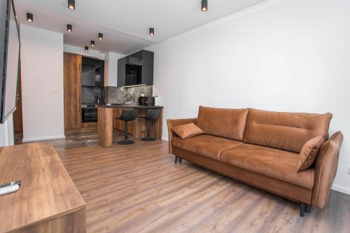 sala de estar con sofá marrón y cocina en Urban Jungle apartament Brooke, en Białystok