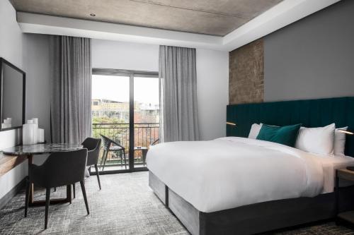 a hotel room with a bed and a desk and a window at The Capital Melrose in Johannesburg