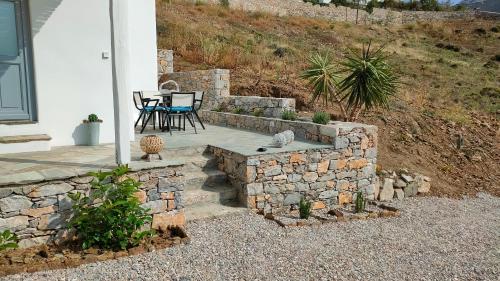 a patio with a table and a stone wall at Scarpathia House in Katapola