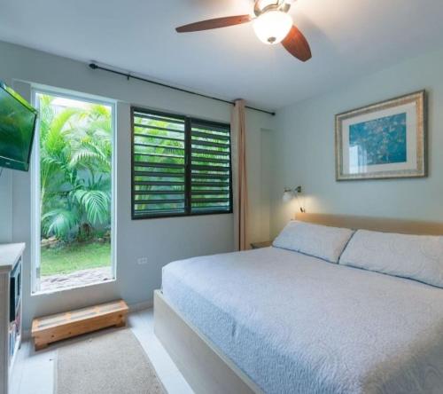 a bedroom with a bed with a ceiling fan and a window at Casa Mia Guest House in Rincon