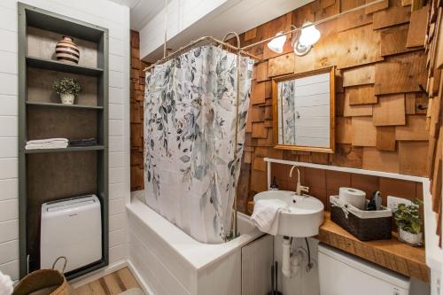 uma casa de banho com uma banheira, um lavatório e um chuveiro em Riverside Log Cabin w Hot Tub Fire Pit Huge Deck em Rileyville