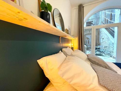 1 dormitorio con 1 cama con un estante en la pared en Le Patio - Rénové et Proche lac, en Nantua