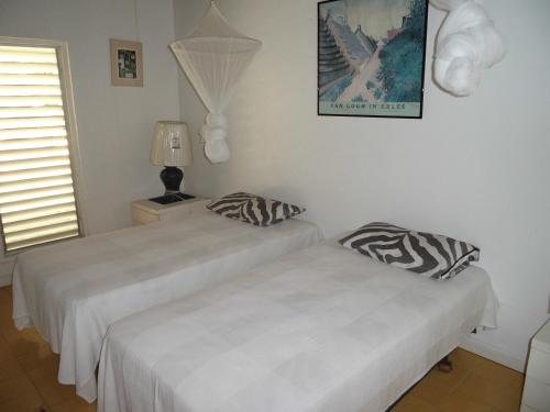 1 dormitorio con 2 camas, lámpara y ventana en Villa Romana, en Freetown Village