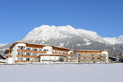 a hotel with a snow covered mountain in the background at Best Western Plus Hotel Alpenhof in Oberstdorf