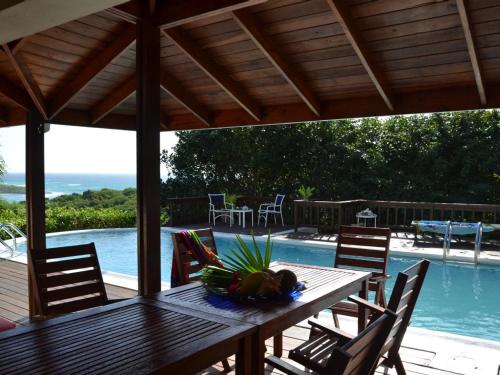 Freetown Village的住宿－Villa Romana，游泳池旁的一张带椅子的木桌