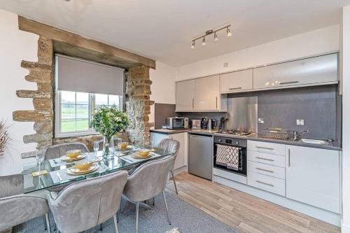 a kitchen with a glass table and chairs and a counter at Harestones - Bridge End Mill by Guestz in Settle