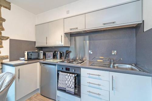 a kitchen with white cabinets and a stove top oven at Harestones - Bridge End Mill by Guestz in Settle