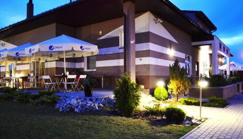 a building with tables and umbrellas in front of it at Hotel Graffit in Świebodzin