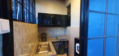 a small kitchen with black cabinets and a sink at Cozy Nest Oasis - Serviced Apartment in Kigali