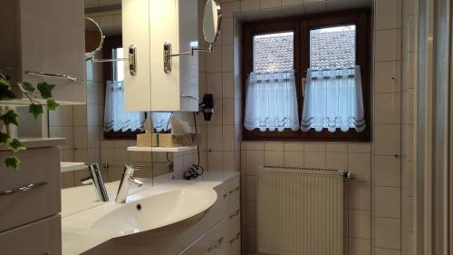La salle de bains est pourvue d'un lavabo, d'un miroir et d'une fenêtre. dans l'établissement FeWo Sonnenschein, Oberstaufen, à Oberstaufen