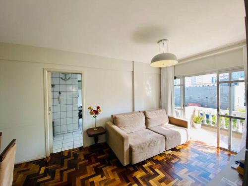a living room with a couch and a large window at Ótima localização quadra mar e central in Balneário Camboriú
