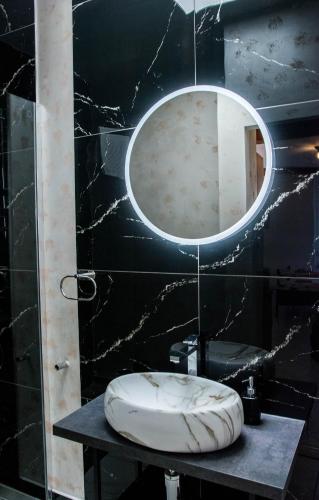 a bathroom with a round mirror on a black wall at Apartmani DA in Piran