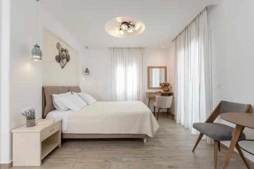 a white bedroom with a bed and a table at Sun Beach Hotel in Naxos Chora