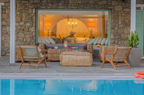 a patio with chairs and a couch and a pool at Mando Pool Villas w Sea Views - Five Bedrooms in Super Paradise Beach