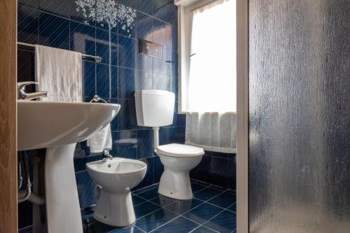 a blue tiled bathroom with a toilet and a sink at Butterfly House in Trappeto