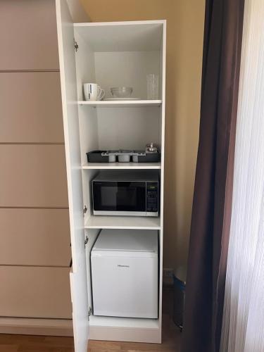 a white book shelf with a microwave on it at Private room, private bathroom, private entrance in private house in Kaunas