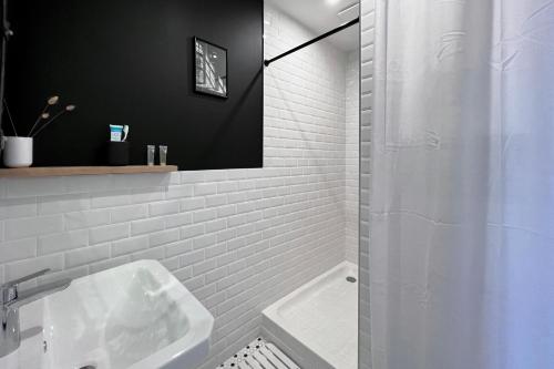 biała łazienka z umywalką i prysznicem w obiekcie Appart 2 personnes à 50m des commerces & mer w mieście Barneville-Carteret