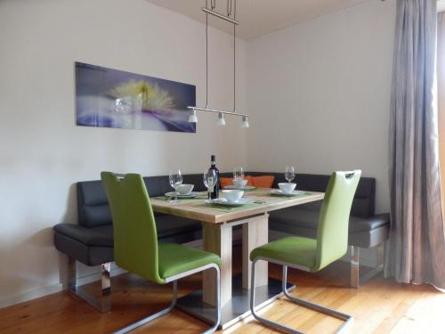 a dining room with a table and green chairs at Ferienhaus Bella Vista in Presseggersee