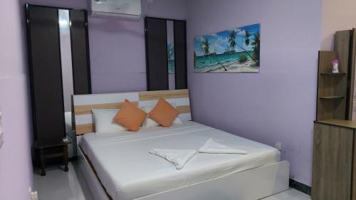 ein kleines Schlafzimmer mit einem weißen Bett und orangefarbenen Kissen in der Unterkunft Sunny Side inn in Midu