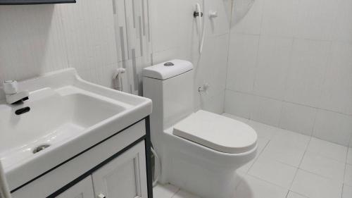 ein weißes Bad mit einem WC und einem Waschbecken in der Unterkunft Sunny Side inn in Midu