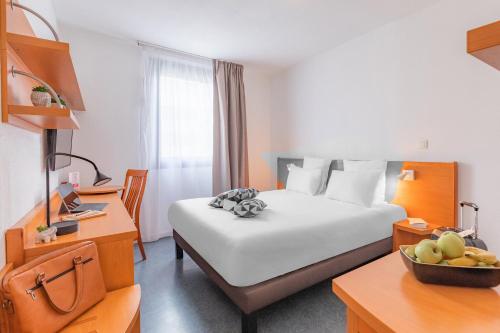 リヨンにあるAppart’City Confort Lyon Gerlandのベッド1台とフルーツ1杯が備わるホテルルームです。