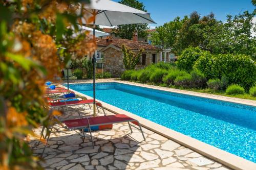 a pool with chairs and an umbrella next to a house at Apartmani Martina in Poreč