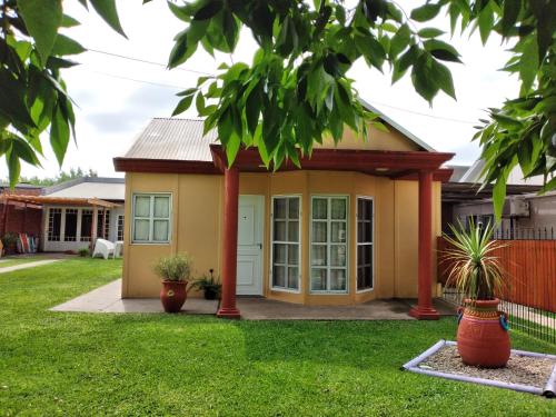 una pequeña casa amarilla con un poste rojo en Alojamiento Turístico Los Pinos en Villa Elisa